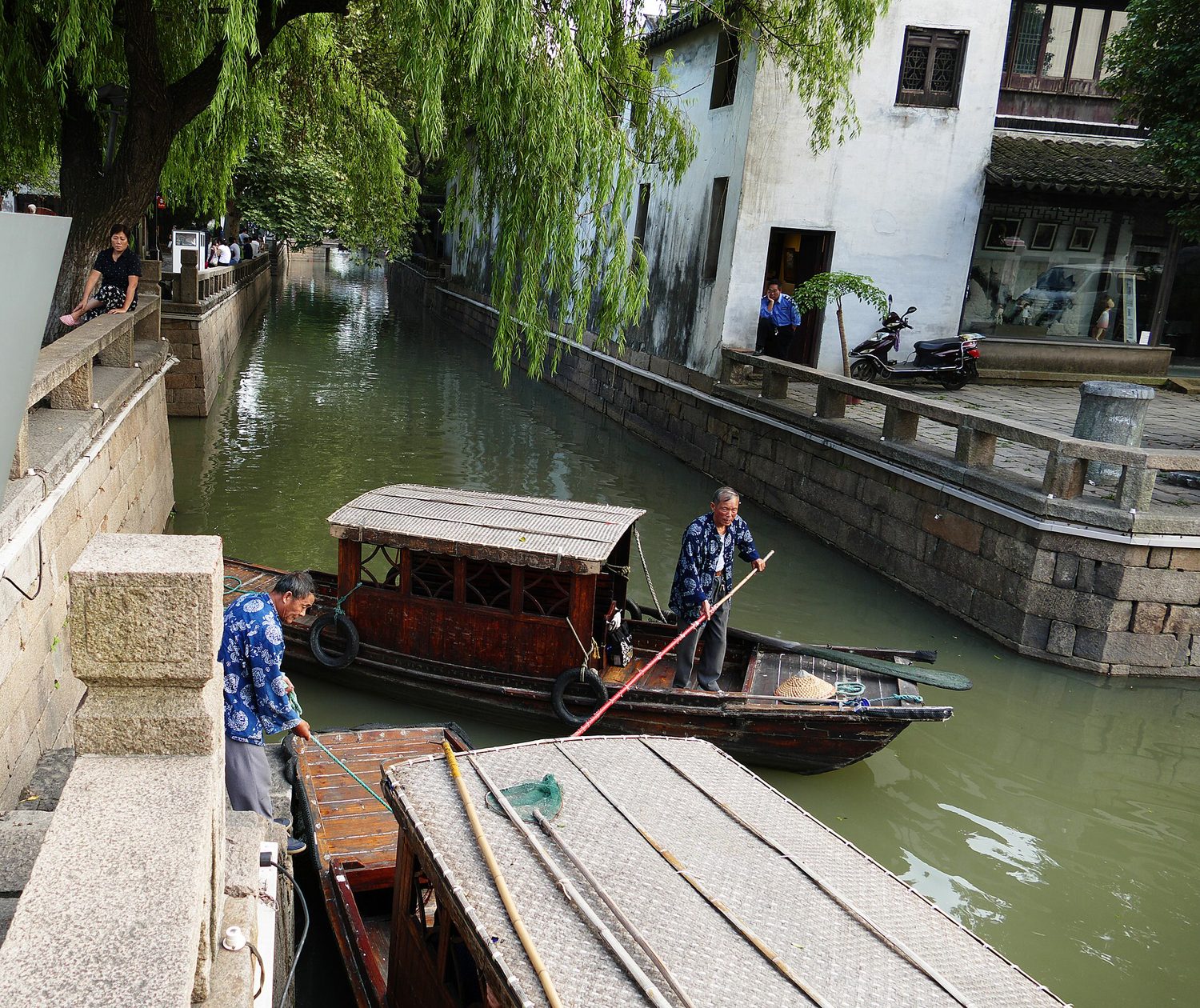 Whitewashed houses and willow trees lining a narrow canal in Suzhou
