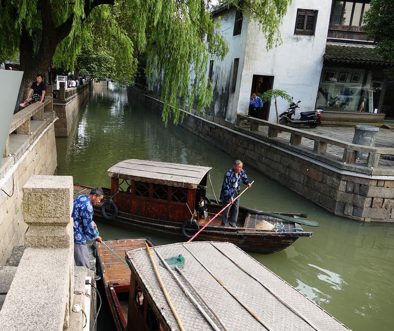 Whitewashed houses and willow trees lining a narrow canal in Suzhou